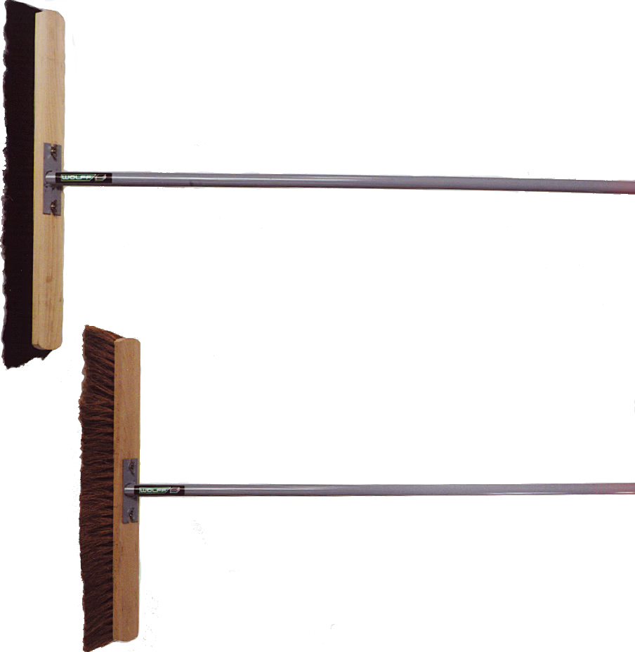 WOLFF_Dummy_15924_broom_2025-08 Studio-style product photo showing two long-handled floor sweepers arranged one above the other on a clean white background. Each tool features a rectangular wooden head mounted to a straight tubular metal handle by a small metal bracket; the top head is fitted with a black rubber squeegee blade suitable for pushing liquids and fine debris, while the lower head has dense brown natural-fiber bristles for sweeping coarser dirt. The composition emphasizes the construction details — wooden blocks, metal fittings and full-length handles — and presents the items as sturdy janitorial or outdoor cleaning tools.