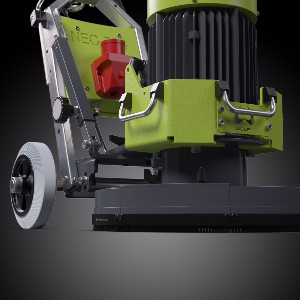 WOLFF_Application Image_NEO330_183050_02_2026-03 Close-up view of a professional floor machine captured in high-contrast black-and-white. The composition focuses on the lower motor and brush housing from a low angle, emphasizing the ribbed industrial electric motor, the textured metal protective casing with two robust stainless-steel handles, and the round polishing base with a dense brush skirt. To the left, a large solid wheel with concentric tread is visible, mounted to a sturdy aluminum frame with adjustment knobs, bolts and hinge elements; the frame plate shows a faint embossed "NEO" while a small nameplate on the housing reads "WOLFF". Directional lighting from above and slightly front-left creates crisp highlights on machined metal surfaces and deep shadows that accentuate form and material, giving the scene a technical, tactile quality. The image conveys scale, weight and mechanical detail—smooth cast parts, brushed metal handles, a knurled adjustment knob, exposed fasteners and rubberized trim—suitable for product catalog imagery or technical documentation.